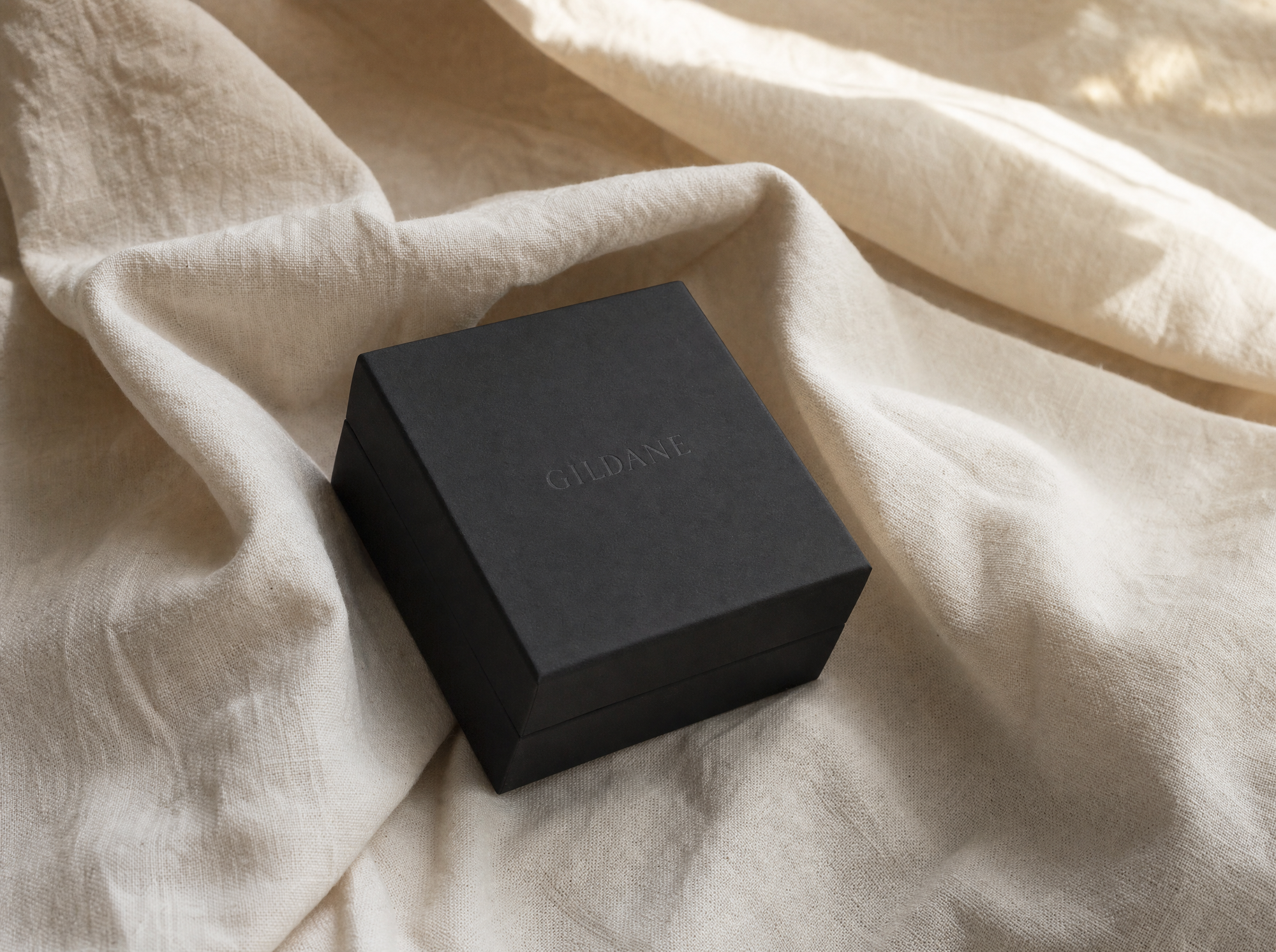 A matte black GILDANE box resting on ivory linen
