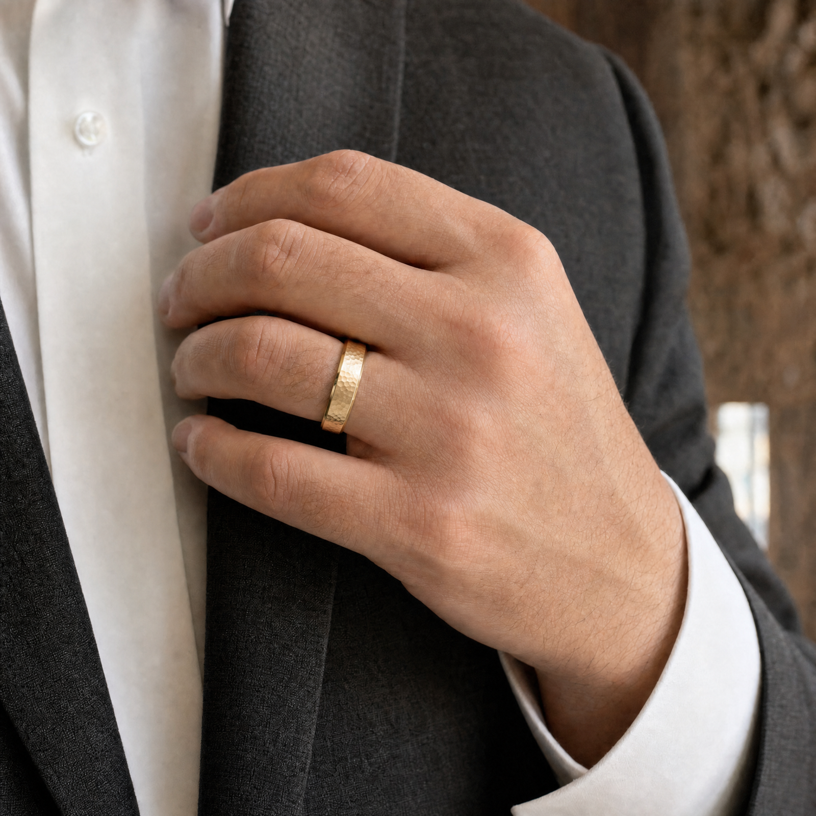 Gold · Hammered — men's 5mm beveled hammered gold wedding band, worn on the hand against a charcoal suit