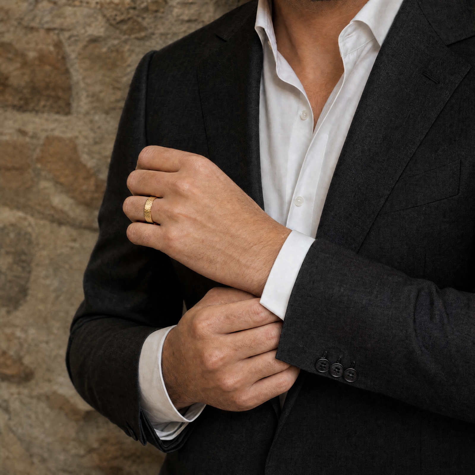 Gold · Hammered — men's 5mm beveled hammered gold wedding band, groom in a charcoal suit wearing the band