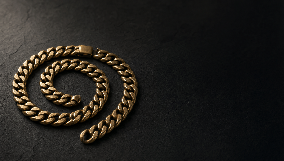 A heavy gold cuban link chain coiled on dark stone
