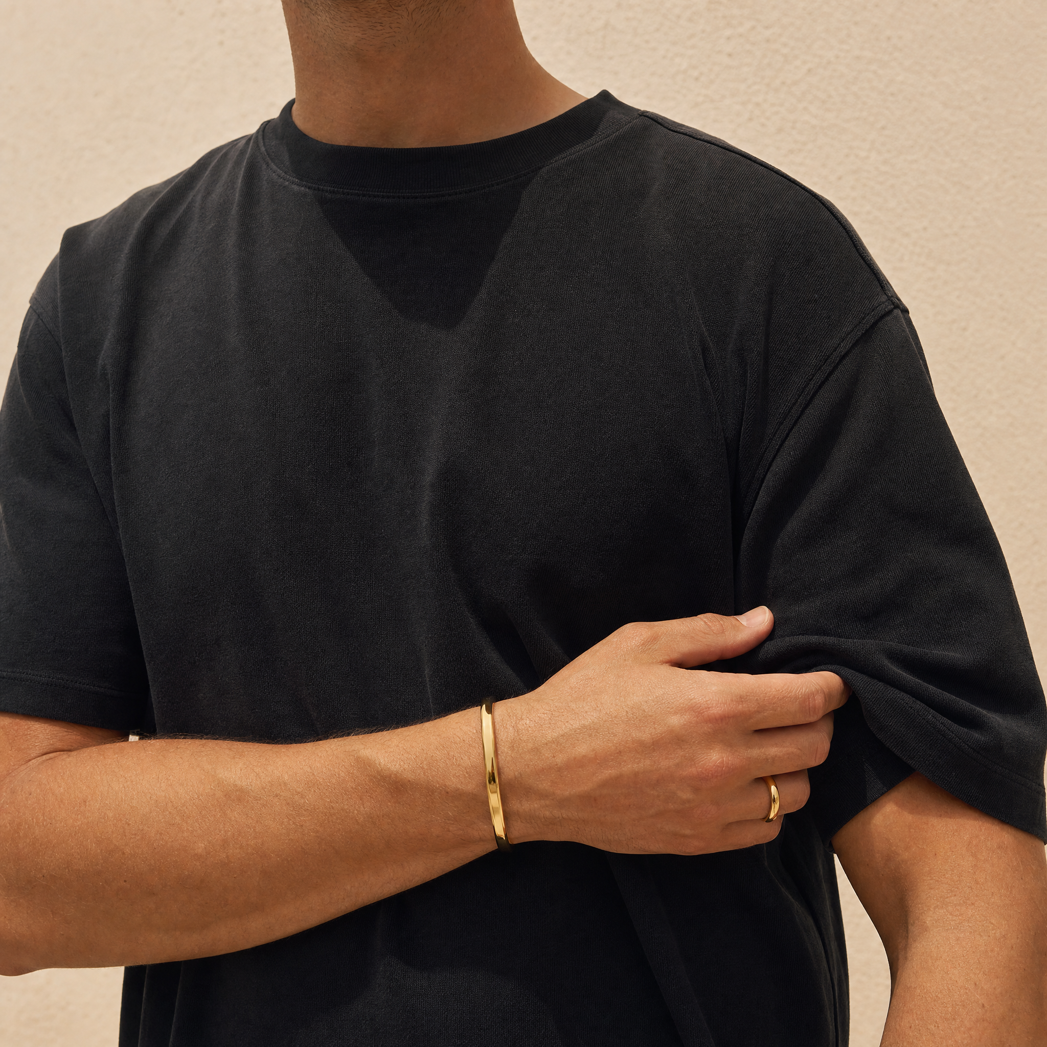 Man wearing the gold cuff and ring in warm daylight