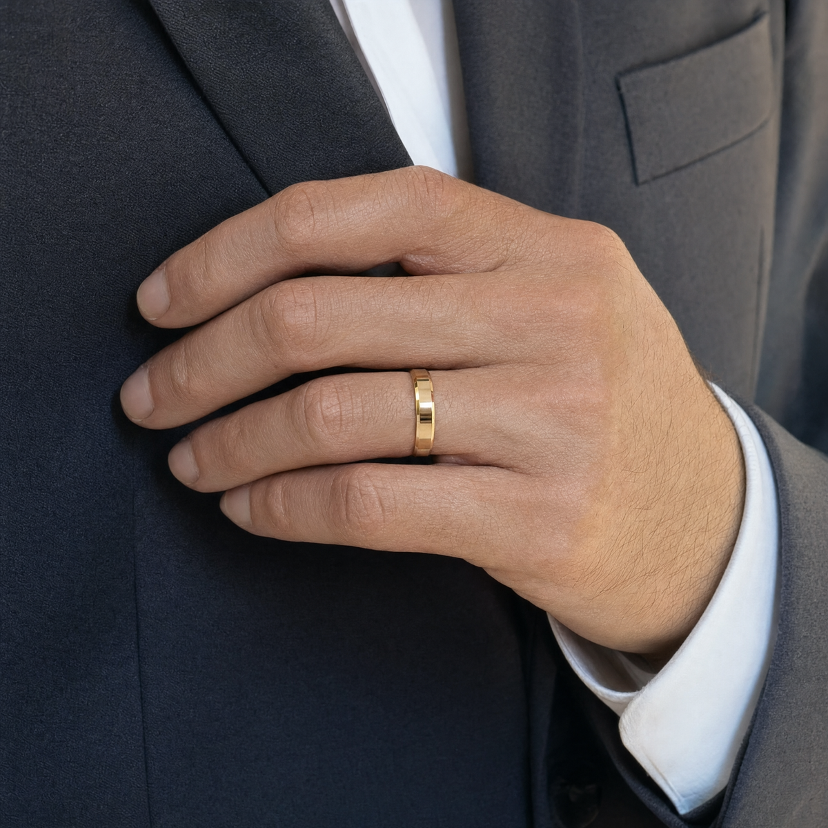 Gold — beveled gold band on the ring finger against a charcoal suit