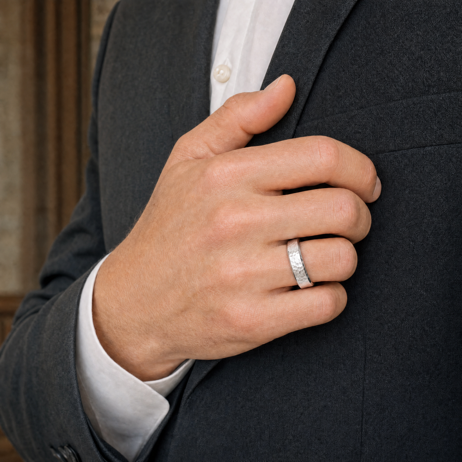 Silver · Hammered — men's 5mm beveled hammered silver wedding band, worn on the hand against a charcoal suit