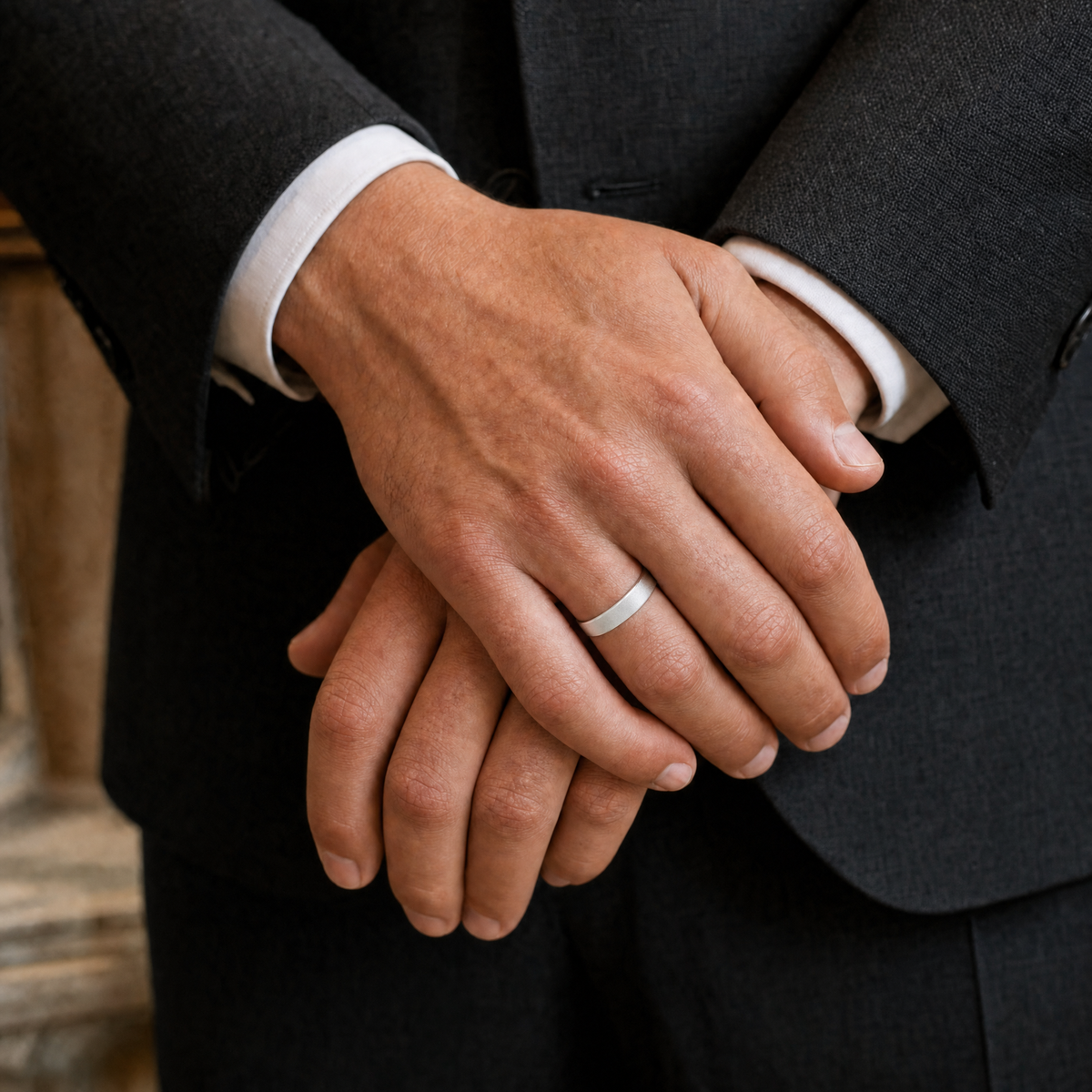 Silver · Ice matte — men's 5mm beveled frosted ice matte silver wedding band, the band at true size on clasped hands in a suit